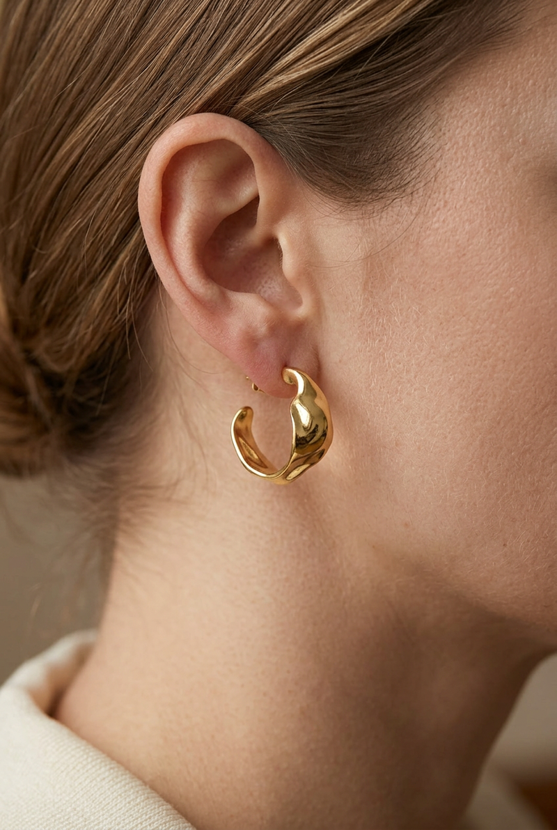 Close-up model wearing the sculpted gold hoop earrings