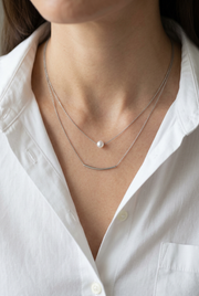 Close-up of the layered necklace on a model wearing a white shirt