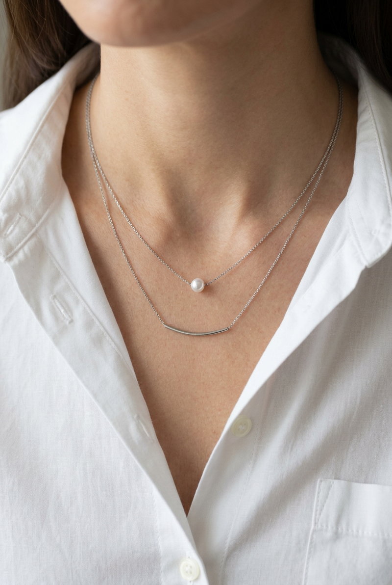 Close-up of the layered necklace on a model wearing a white shirt