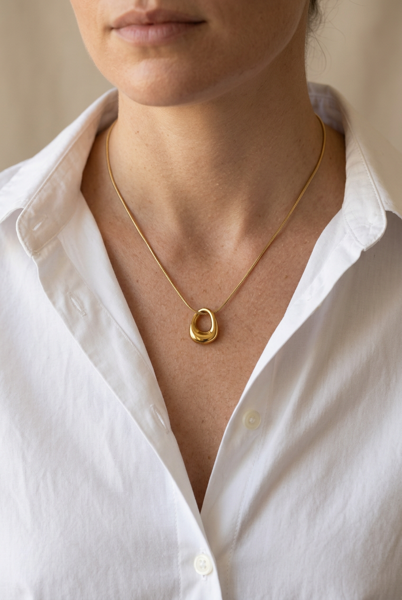 Gold charm necklace on a model wearing a white shirt
