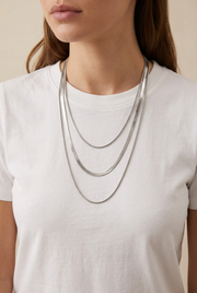 Model wearing the three-layer silver necklace over a white T-shirt