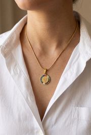 Necklace close-up with a smaller pendant and white shirt