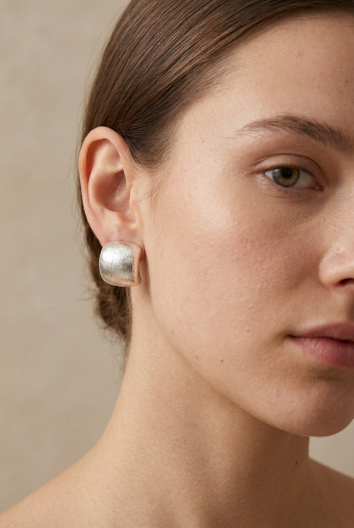 Young adult model wearing the brushed silver rounded-square earrings in close-up