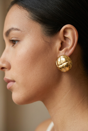 Young adult model wearing the rounded gold statement earring in a daylight close-up
