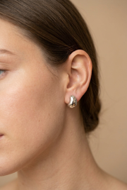 Young adult model wearing the small sculptural silver earrings in close-up