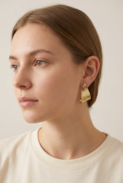 Young adult model wearing the textured gold earrings